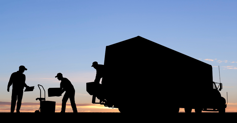 Silhouette of a moving crew loading a moving truck at dusk