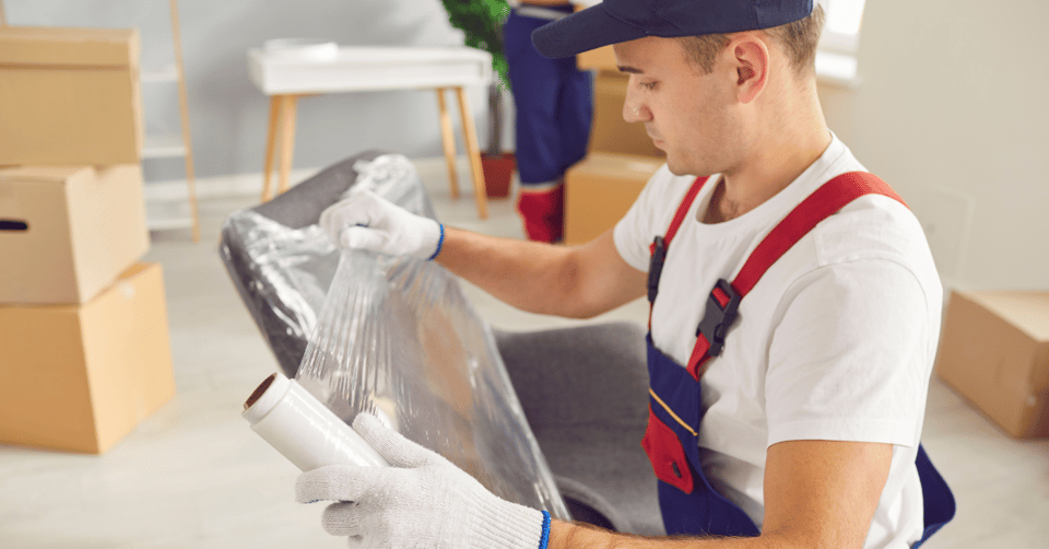 Professional mover wrapping furniture with plastic wrap